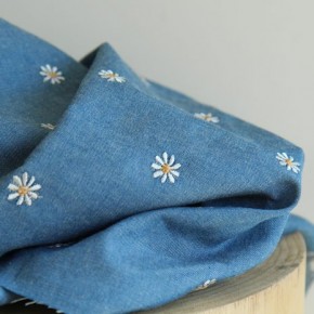 tissu denim bleu brodé de pâquerettes